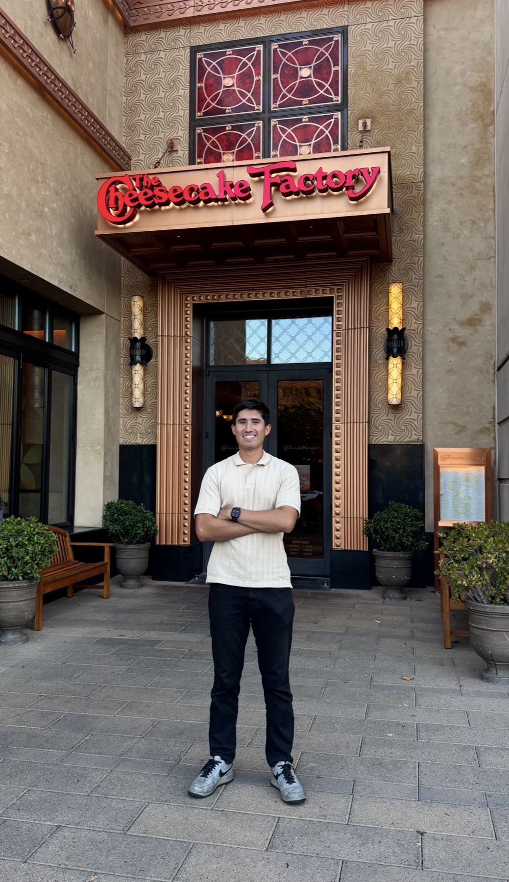 Mateo standing in front of The Cheesecake Factory restaurant entrance